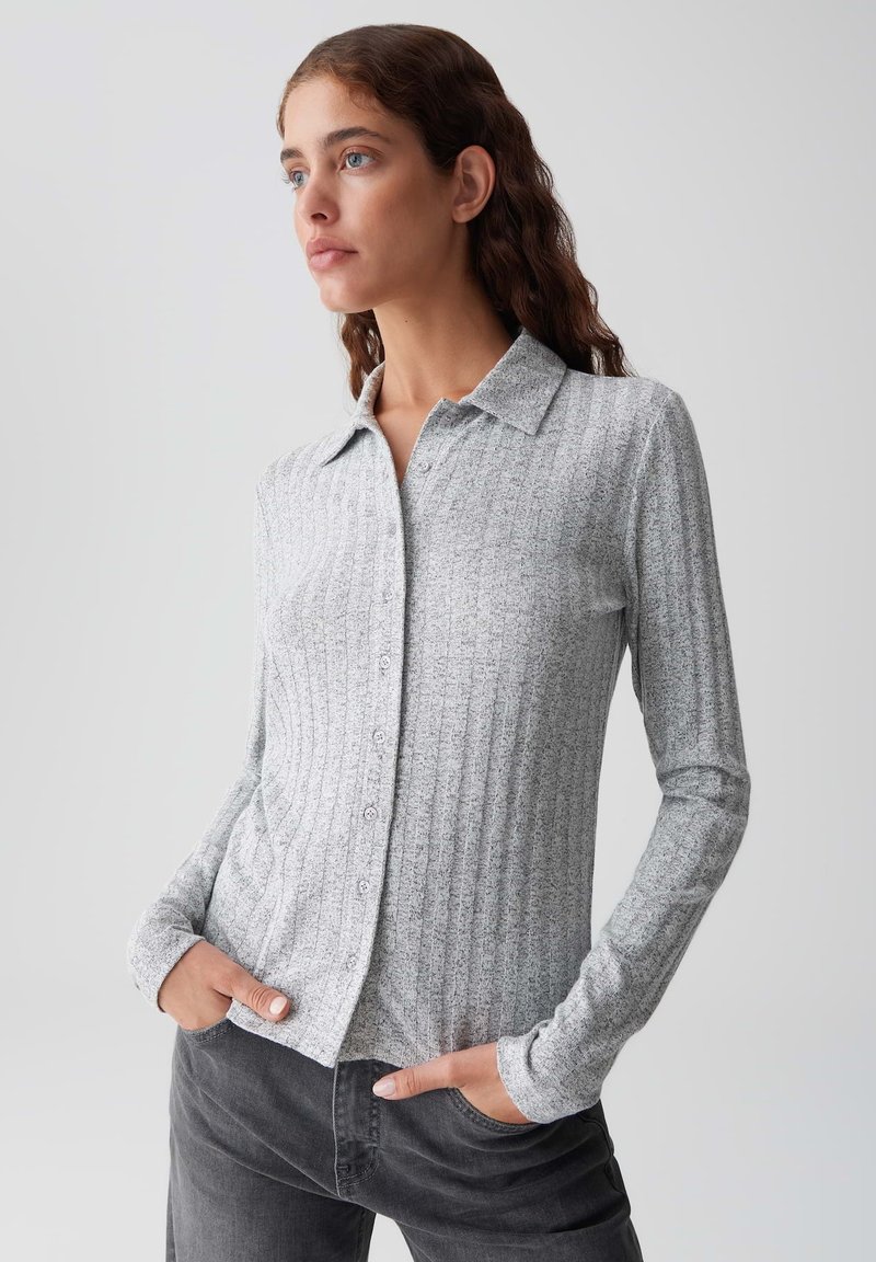 Maglietta a maniche lunghe grigia a coste con colletto e chiusura a bottoni, caratterizzata da una texture morbida e un design aderente.