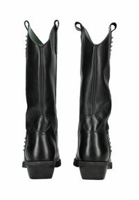 Bottines en cuir noir avec un talon large et robuste, présentant une finition lisse, des coutures courbées et du matériel décoratif le long des côtés.