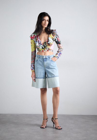 Kvetinový crop top s volánovým výstrihom, v kombinácii so svetlomodrými denimovými šortkami s kontrastným dolným pásom. Čierne popruhové lodičky.