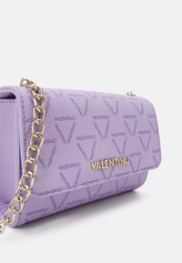 Lila nylonhandväska med guldkedjesnodd och upprepat "Valentino"-logomönster, med en magnetknäppning och slät yta.