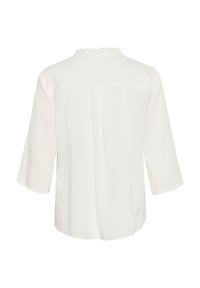 Top din in cu un guler rotund ușor volanțat, mâneci 3/4 și o croială lejeră. Design simplu cu un detaliu de cusătură pe spate.
