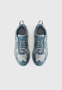 Teal and gray athletic shoes with a mesh upper, lace-up design, padded tongue, and rubber outsole. Features ASICS logo and reflective accents.
