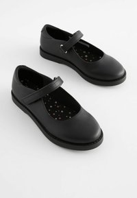 Chaussures Mary Jane en cuir noir avec un bout arrondi et une bride sur le cou-de-pied. La semelle intérieure texturée noire présente un motif d'étoiles en rose et blanc.