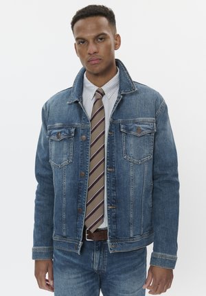 Jeansjacke in Mittelblau mit Kragen, Knopfleiste vorne, zwei Brusttaschen und geradem Schnitt, kombiniert mit einem gestreiften Hemd und einer Krawatte.