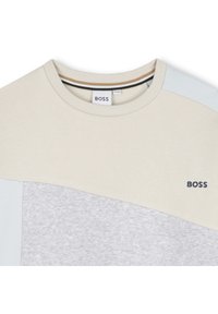 Light beige and gray sweatshirt with a crew neckline, contrasting pastel shoulder accents, and a small dark blue "BOSS" logo on the chest.