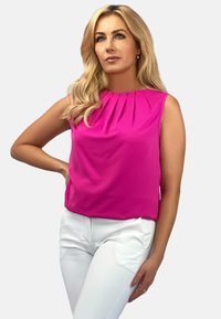 Fuksjowa bezrękawnik z plisami przy dekolcie, zestawiony z białymi spodniami. Gładka tekstura i swobodny krój. Prosty i nowoczesny design.