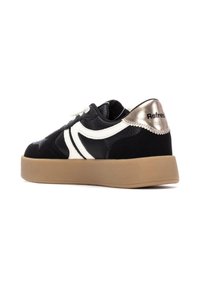 Zapatilla negra con acentos blancos, tela texturizada y detalle del talón en oro metálico. Cuenta con una suela de goma gruesa y cordones.