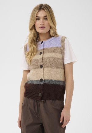 Kvinde iført en knappet, ærmeløs strikvest med horisontale beige, brune, grå og lavendelstriber over en hvid T-shirt.