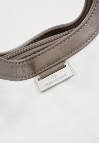 Weißer Lederhandtasche mit grauen Akzenten, mit einem Reißverschluss und einem silbernen Logo-Tag. Glatte Textur mit sichtbaren Nähten.
