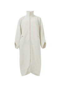 Abrigo cremoso con cremallera y collar alto, mangas oversized y bolsillos laterales. Tela suave con una textura lisa y dobladillo curvado.