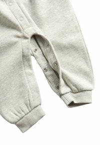 Un body en coton gris clair avec des boutons-pression en bas, des poignets côtelés et une texture douce, présentant un design simple et minimaliste.