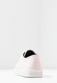 Růžová plátěná slip-on obuv s bílou gumovou podrážkou, s minimálním šitím, značkovou visačkou na patě a zaobleným zadním designem.