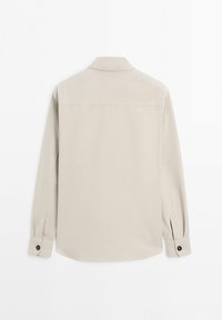 Beigefarbenes langärmeliges Hemd mit geknöpften Manschetten, Hemdkragen und Naht über dem oberen Rücken, flach von hinten auf weißem Hintergrund dargestellt.