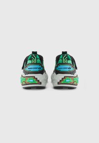 Een paar zwarte en groene sneakers met een gepixeld ontwerp en de tekst "MEGA-CRAFT" op de achterkant, tegen een effen witte achtergrond.