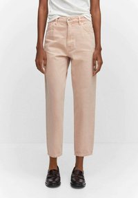 Pantalon en denim rose clair avec une taille haute, coupe droite, poches avant et fermeture à bouton unique, associé à des mocassins foncés.