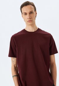 Bordeaux bomulds t-shirt med rund hals og korte ærmer, med en glat overflade og enkelt design. Minimalistisk stil.