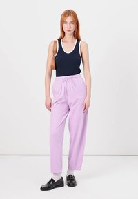 Navy tank top with white trim, paired with light purple elastic-waist pants. Accessories include a small brown bag and black shoes.
