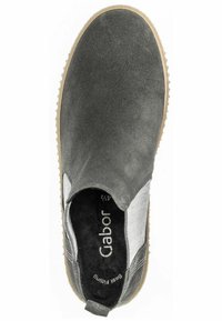 Scarpa slip-on in suede grigio con pannello laterale testurizzato, suola in gomma marrone e rivestimento morbido. Presenta un logo sulla soletta.