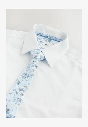 Weißes Hemd mit einem hellblauen Blumenbindeschal. Das Hemd besitzt eine glatte Textur, während die Krawatte ein Blumenmuster auf einem weichen Stoff zeigt.