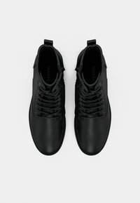 Bottines en cuir noir avec une finition lisse, bout rond et lacets. Dotées d'une languette à l'arrière pour un enfilage facile.