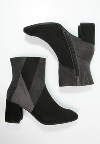 Schwarze und graue Ankle Boots aus Wildleder, mit Blockabsatz, schrägem Farbblockdesign und einem seitlichen Reißverschluss mit kontrastierender Naht.
