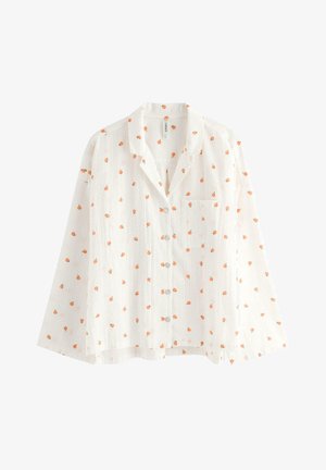 Hvid skjorte med lange ærmer og knapper, med lille orange frugtmønster og en brystlomme på venstre side.