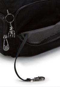 Sort stofpose med lynlås, prydet med en blank abe charms på en nøglering og klips, glat tekstur og diskrete syninger.