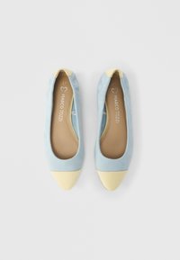 Φλατ μπαλαρίνες από γαλάζιο σουέντ με μυτερή κίτρινη μύτη και αντίθετη λεπτομέρεια στη φτέρνα, με μπεζ πάτο που φέρει το λογότυπο της μάρκας.