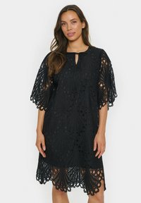 Black lace dress with intricate circular cutouts and a scalloped hem. Features short, fluttering sleeves and a keyhole neckline design.