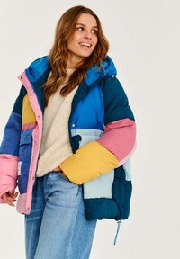 Bunda typu puffer má vícebarevné panely v modré, růžové, žluté a zelené barvě. Má kapuci, přední kapsy a texturovaný povrch.