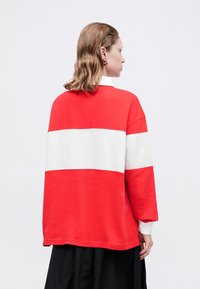 Červená a biela pruhovaná oversized mikina s okrúhlym výstrihom a dlhými rukávmi, s textúrovanou tkaninou a voľným strihom.