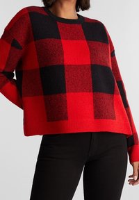 Suéter de cuadros rojo y negro con un corte relajado, puños y dobladillo acanalados. Presenta un cuello redondo y una tela suave y texturizada.