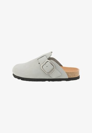 Grå ruskinds slip-on klump med en bred rem, metalspænde detalje og en kork sål. Sålen er lavet af tekstureret sort gummi for bedre greb.