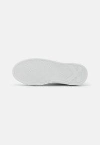 Semelle de sneaker en caoutchouc blanc avec un motif texturé et ondulé, et un logo "K" bien en vue sur le côté, conçue pour l'adhérence et la durabilité.