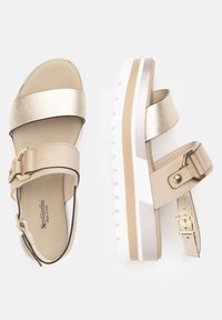 Plattform-Sandalen in einem beigen und goldmetallischen Farbschema. Verfügen über zwei breite Riemen, eine verstellbare Schnalle am Knöchel und eine strukturierte weiße Sohle.