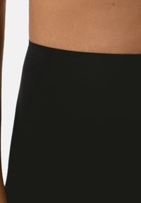 Leggings neri aderenti con una superficie liscia, caratterizzati da una vita alta e un design minimalista. Nessun motivo visibile o dettagli hardware.