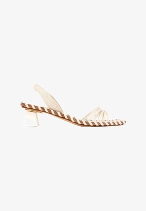 Sandale beige à bride arrière avec plusieurs fines lanières aux orteils, semelle marron avec bordure tressée blanche, et petit talon bloc blanc.
