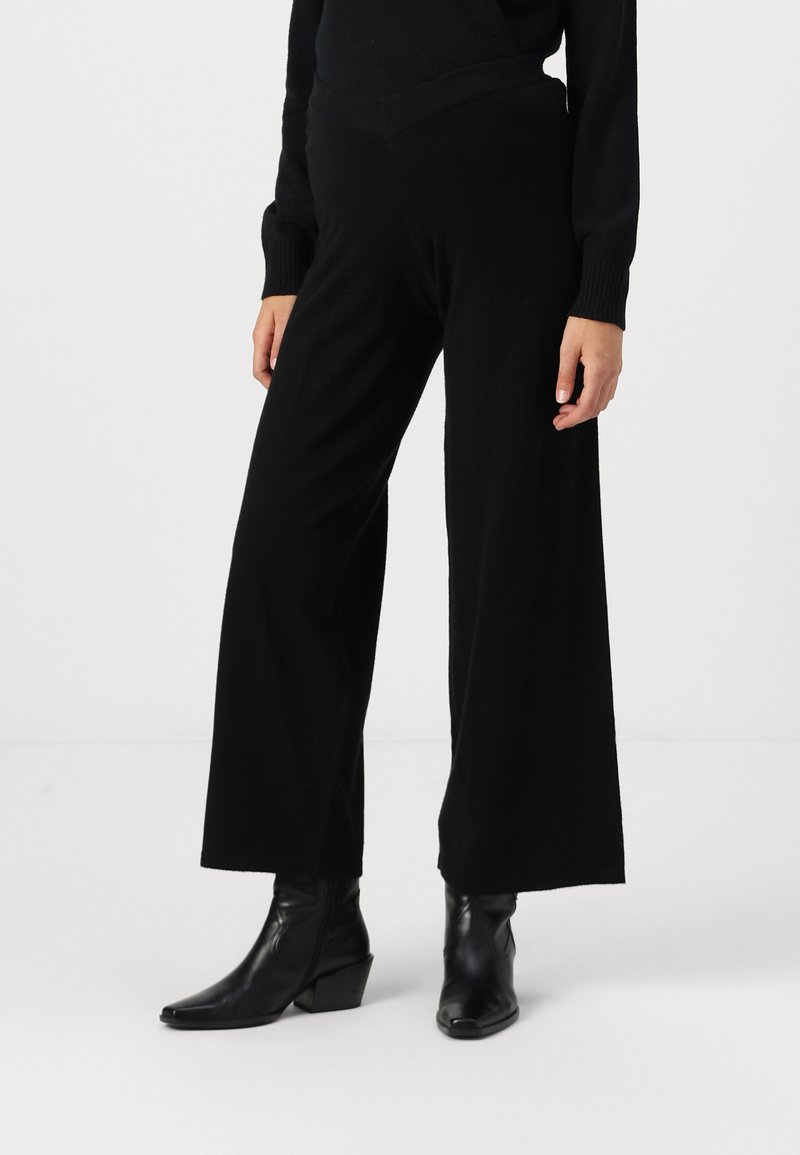 Black wide-leg trousers made of soft fabric. Features a mid-rise waistband, smooth texture, and a relaxed fit extending to the ankles.