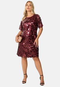 Bordeaux paljetterklänning med korta ärmar, rund halsringning och lös passform. I kombination med en liten metallisk kuvertväska och svarta klackar med remmar.