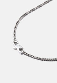 Colar de metal prateado com um design de corrente trançada e fecho de clasp. Textura suave, espessura média e acabamento brilhante.