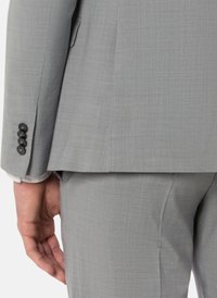 Grauener Anzug mit strukturiertem Stoff, geradem Schnitt und Knopfmanschetten-Detail. Die sichtbare Hand befindet sich in der Nähe der Taille.
