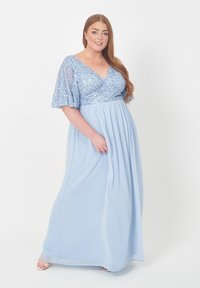 Ljusblå maxiklänning med paljett-bodice, V-ringning och fladdrande ärmar; flödande kjol med rynkad midja för en mjuk silhuett.