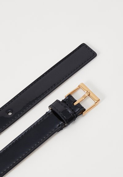 Svart lackläder armbandsrem med en guldig rektangulär spänne, med sömnadsdetaljer längs kanterna och en slät, glänsande yta.