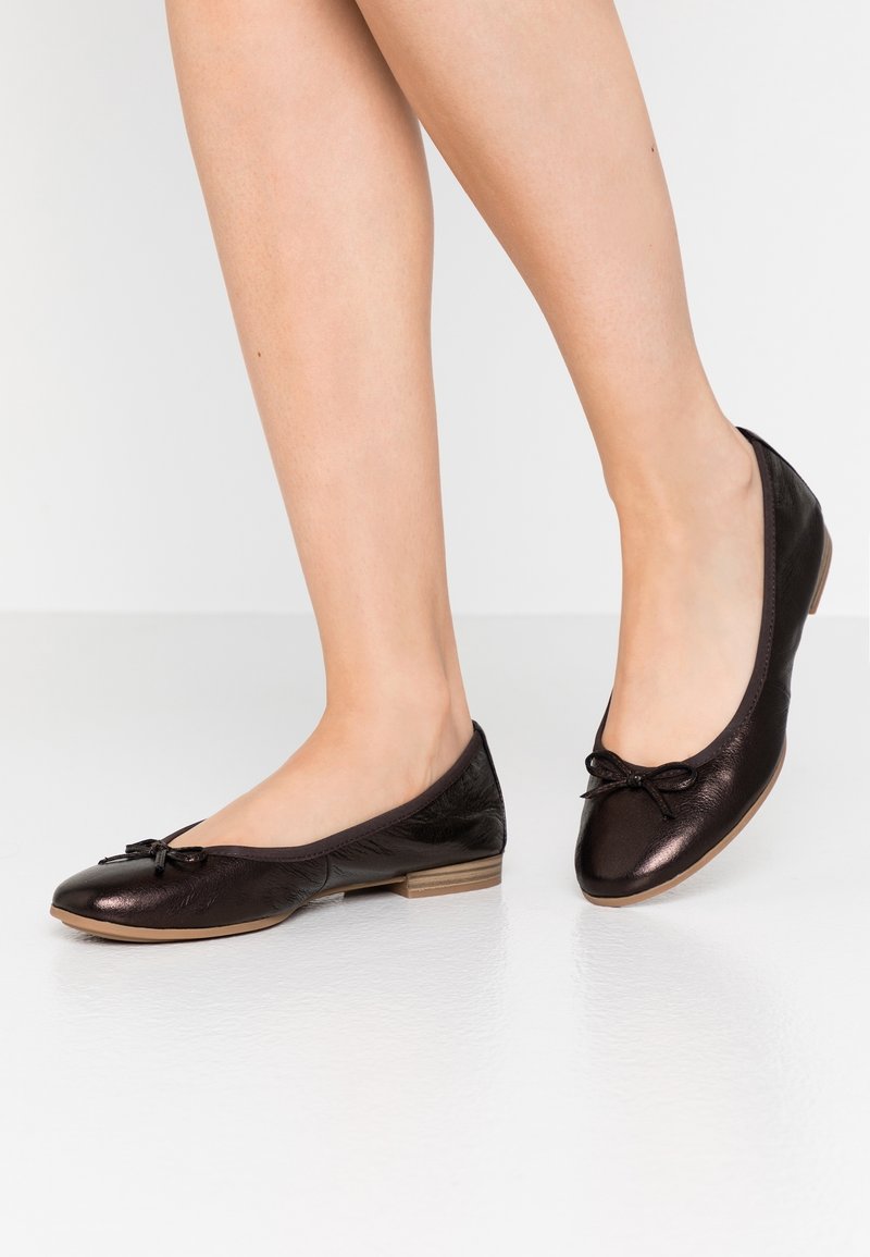 Ballerine in pelle nera con un acrilico a fiocco, punta arrotondata e tacco basso. Finitura testurizzata e superficie liscia.