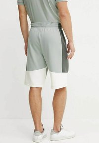 Pantaloni corti sportivi grigi con vita elastica, caratterizzati da una parte inferiore bianca e accenti laterali neri, realizzati in un tessuto leggero.