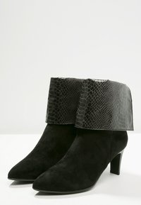 Botines negros con un puño de estampado de serpiente texturizado, material de ante, punta afilada y un tacón medio. El puño contrasta con la parte inferior del botín.