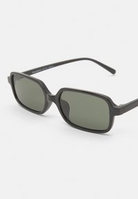 Black rectangular sunglasses with dark green lenses. Made of plastic, featuring a subtle thickness and smooth texture, with curved arms.