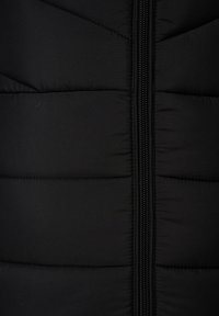 Zwarte puffer vest met een verticale rits. De stof heeft doorgestikte secties, wat zorgt voor een gewatteerde textuur met een gladde afwerking.