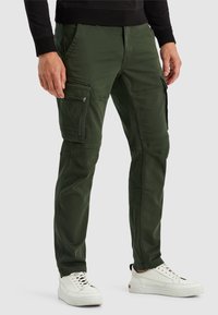 Grüne Cargo-Hosen mit mehreren Reißverschlusstaschen, slim-fit Design, aus strapazierfähigem Material, kombiniert mit weißen Sneakers.