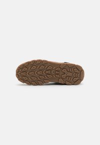 Semelle extérieure en caoutchouc brun avec des motifs de relief texturés, comprenant des rainures et des éléments de traction. Profil plat adapté à divers terrains.